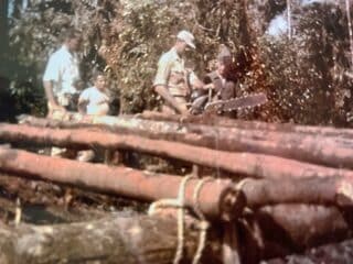 3 Steve Honore watched John Stahlmann cut more timbers for the helipad.
